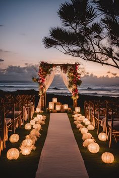 an outdoor wedding setup with lanterns and flowers on the aisle at dusk, overlooking the ocean