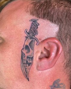 a man with a tattoo on his head has a knife stuck in the side of his ear