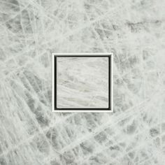 a square white marble tile with a metal grate in the middle on a gray background