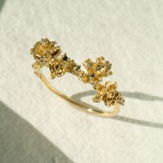 a gold ring with flowers on it sitting on top of a white cloth covered table