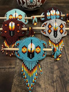 four beaded native american dream catchers sitting on top of a wooden table