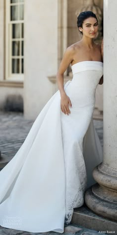 a woman in a wedding dress leaning against a column