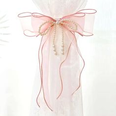 a pink bow with pearls hanging from it's side