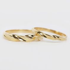 two gold wedding rings sitting on top of each other