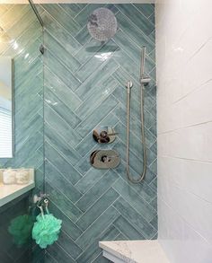 a bathroom with green and white tile on the walls, shower head, and hand held showerhead