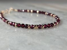 This gorgeous bracelet is made with vivid scarlet red faceted round Garnet and highly polished 14k Yellow Gold filled beads. The deep red gemstones are perfectly complimented by the warm yellow of 14k gold, and combined, come together to become a stunning piece of art, and jewelry.        ∆  M A T E R I A L S  ∆ * 3.5mm Faceted Round Red Garnet * 14k Gold Filled Hardware and Spring Ring Clasp ( 14k Gold Filled Lobster Claw Clasp Available as Add On) * Your Choice of Gold Filled Spacers:  ---2mm(Small) Round Beads ---2.5mm(Medium) Round Beads ---3mm(Large) Round Beads ---3mm Rondelles      ∆  14K  G O L D - F I L L E D  ∆ Thirty-Two Karits exclusively hand-crafts our items by using gold-filled materials, high-quality genuine gemstones, and the highest professional grade beading wire with th Red Faceted Rondelle Jewelry, Red Rondelle Gemstone Beads Bracelets, Faceted Garnet Round Bead Jewelry, Red Faceted Round Bead Bracelets, Red Faceted Round Bracelets, Red Faceted Elegant Bracelets, Elegant Red Faceted Beaded Bracelets, Elegant Red Faceted Bracelets, Garnet And Gold