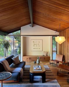 a living room filled with lots of furniture and wooden walls covered in wood planks