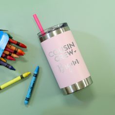 a cup with a straw and some crayons next to it