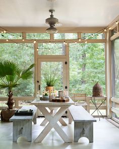 a table and bench in a room with large windows