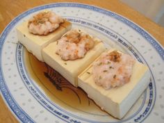 three pieces of food sitting on top of a blue and white plate next to a wooden table