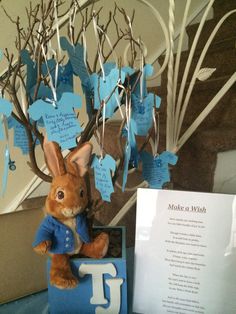 a stuffed rabbit sitting on top of a table next to a tree with blue leaves