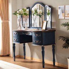 a blue vanity with mirror and flowers in vases on the table next to it