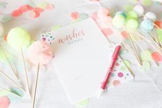 a notepad sitting on top of a table next to some pom poms