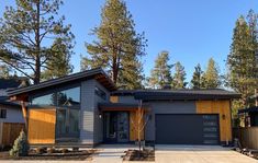 a house that is in the middle of some trees and has two garages on each side