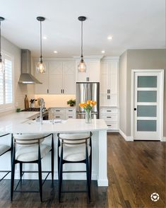 a kitchen with white cabinets and an island in the middle is surrounded by stools