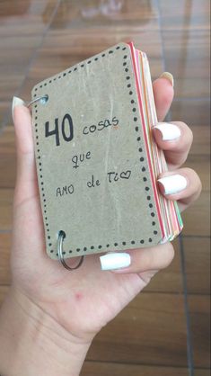 a person holding up a small book with writing on the front and back pages in spanish