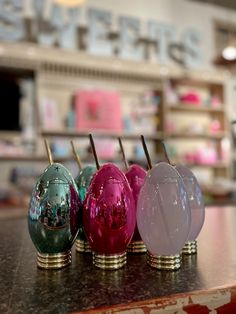 four different colored glass vases sitting on top of a counter in front of a store