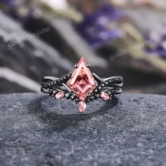 a pink diamond ring sitting on top of a rock