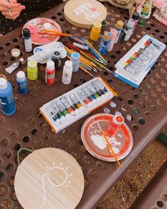 the table is covered with art supplies such as paints, brushes and paper plates on it