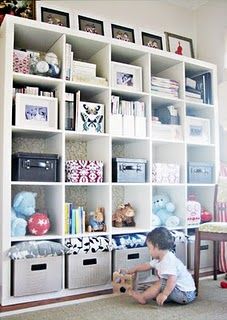 a child playing with toys in front of a bookshelf filled with stuffed animals