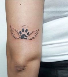 a woman's arm with a paw and angel wings tattoo on the left side