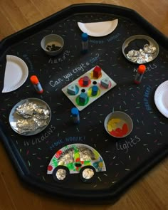 a black tray topped with lots of different types of crafts and paper plates on top of it