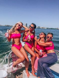 four women in pink bikinis are sitting on a boat and posing for the camera