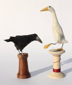 two birds are standing on top of a thread spool and one bird is perched on the end of a wooden spool