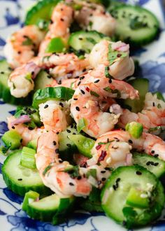 shrimp and cucumber salad with sesame seeds on a blue and white floral plate