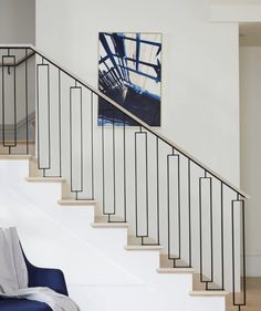 a blue chair sitting in front of a stair case next to a painting on the wall