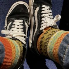 someone's feet wearing black and white sneakers on a blue carpeted area with multi - colored socks