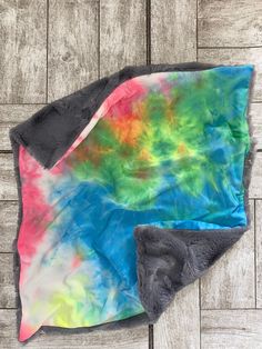 two blankets are laying on the floor next to each other, one has a colorful tie - dyed design