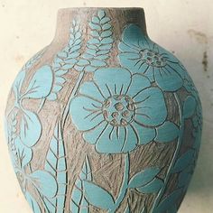 a blue and brown vase sitting on top of a white table next to a wall