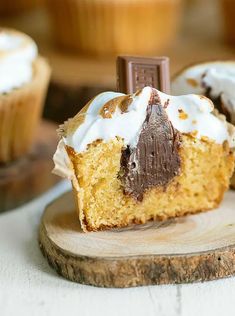 a cupcake with white frosting and chocolate on top is sitting on a wooden board