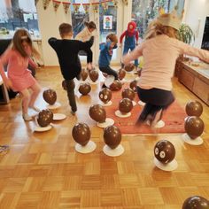 a group of children playing with chocolate balls in a room filled with other kids and adults