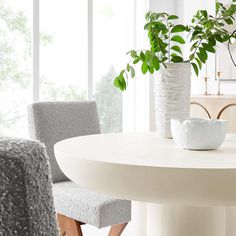 a white table with two chairs next to it and a plant in a vase on top