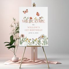 a welcome sign sitting on top of a easel next to a potted plant