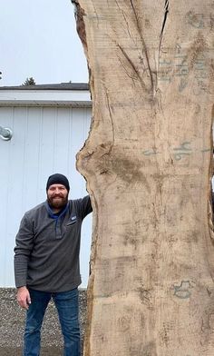 a man standing next to a large piece of wood that has been carved into it