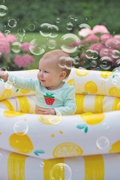 a baby sitting in an inflatable pool with bubbles