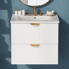 a white sink sitting under a round mirror next to a wall mounted faucet