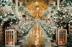 an elaborately decorated hall with flowers and greenery on either side, surrounded by candles