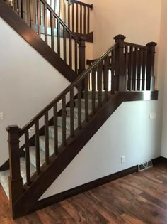 an empty room with wooden stairs and hard wood flooring