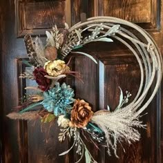 a wreath with feathers and flowers on the front door