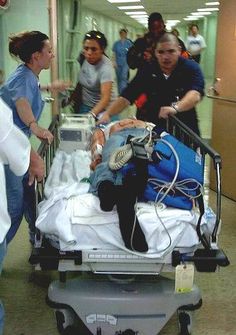 several people standing around a hospital bed with medical equipment on it and one person pushing the cart