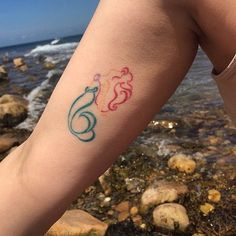 a little mermaid tattoo on the left arm and right leg, with an ocean scene in the background