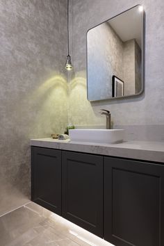 a bathroom with a sink, mirror and lights on the wall above it's counter