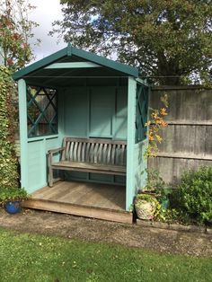 a wooden bench sitting in the middle of a yard next to a tree and fence