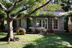 a house with potted plants in front of it and an outdoor dining table on the lawn