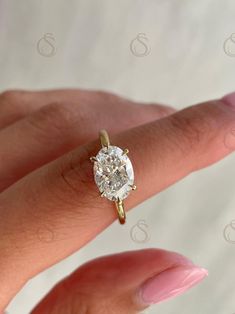 a woman's hand with a diamond ring on top of her finger, showing the center stone