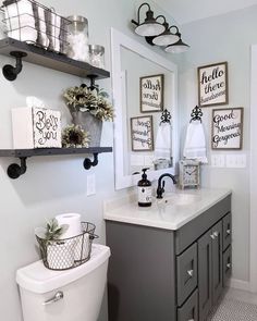 a white toilet sitting next to a sink in a bathroom under pictures on the wall